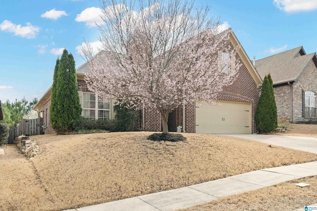 view of property hidden behind natural elements with a garage, brick siding, concrete driveway, and fence