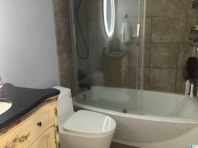 bathroom featuring toilet, bath / shower combo with glass door, and vanity