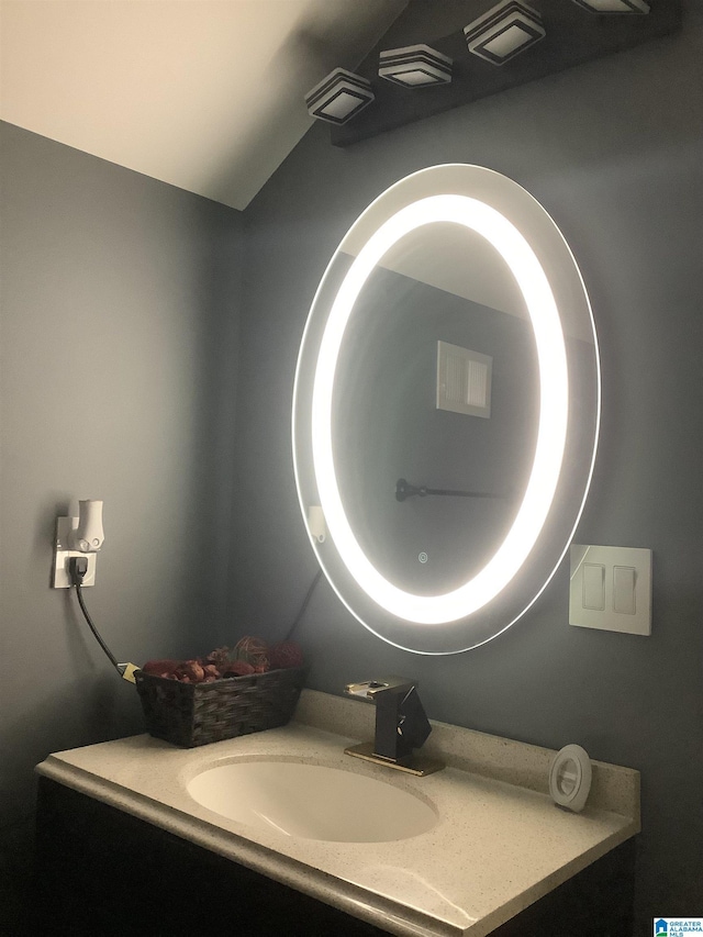 bathroom with lofted ceiling, vanity, and visible vents