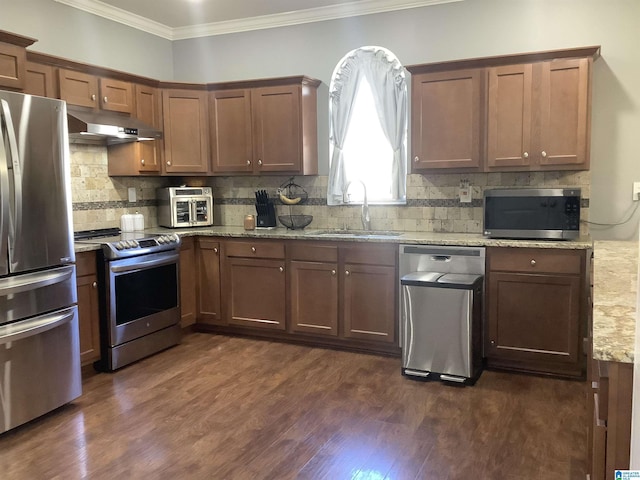 kitchen featuring under cabinet range hood, a sink, appliances with stainless steel finishes, dark wood-style floors, and crown molding