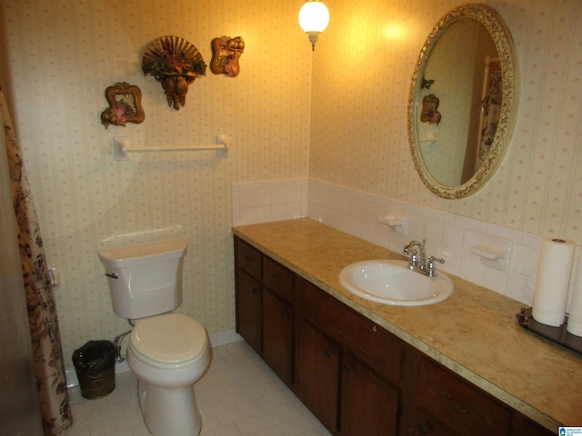 bathroom with toilet, tile patterned floors, vanity, and wallpapered walls