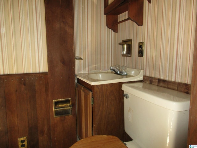 bathroom featuring vanity, toilet, and wallpapered walls