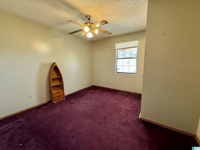 spare room with a textured ceiling, carpet flooring, a ceiling fan, visible vents, and baseboards