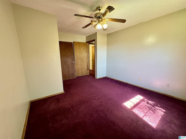 spare room featuring ceiling fan, baseboards, dark colored carpet, and a textured ceiling