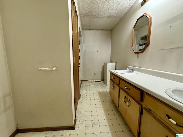 bathroom featuring a textured ceiling, a sink, baseboards, tile patterned floors, and double vanity