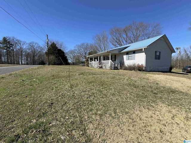 view of front facade featuring covered porch, metal roof, and a front lawn