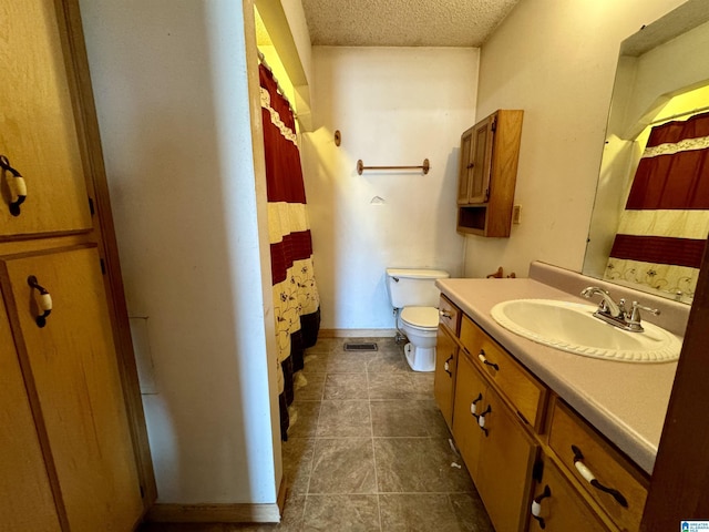 bathroom with baseboards, visible vents, toilet, a textured ceiling, and vanity