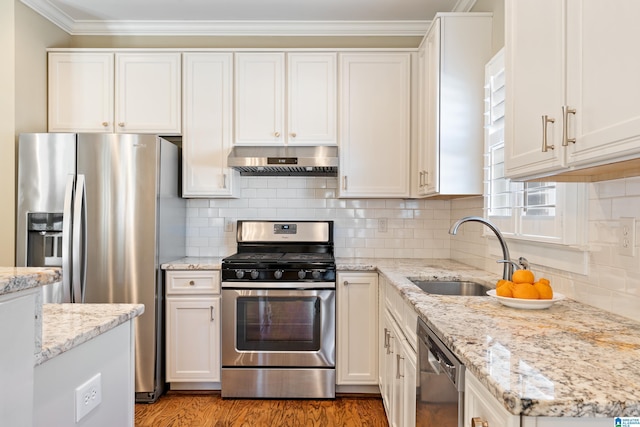 kitchen featuring white cabinets, stainless steel appliances, crown molding, under cabinet range hood, and a sink