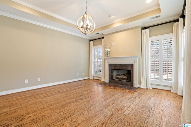 unfurnished living room with visible vents, baseboards, a premium fireplace, ornamental molding, and a tray ceiling