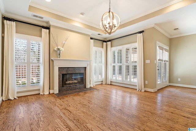 unfurnished living room featuring a tray ceiling, visible vents, ornamental molding, a high end fireplace, and wood finished floors