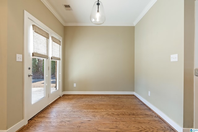 empty room with ornamental molding, visible vents, light wood-style flooring, and baseboards