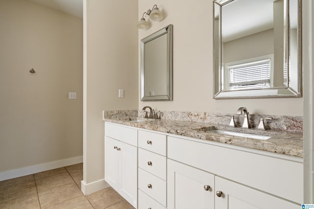 full bathroom featuring baseboards, double vanity, a sink, and tile patterned floors