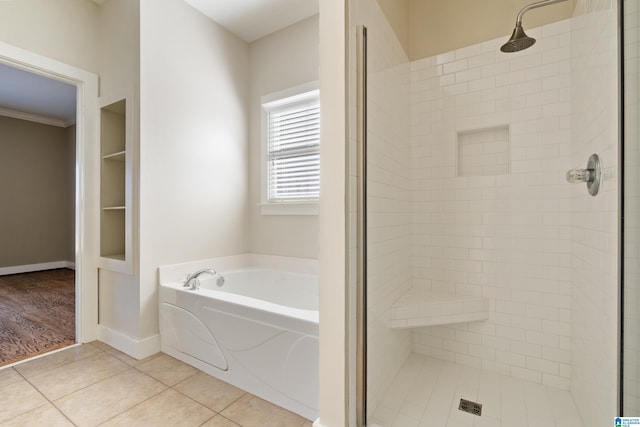 bathroom with a stall shower, baseboards, a garden tub, tile patterned flooring, and crown molding