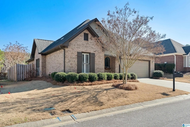 view of front of house featuring driveway, brick siding, an attached garage, and fence