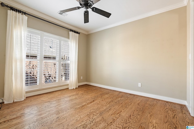 unfurnished room with crown molding, visible vents, a ceiling fan, wood finished floors, and baseboards