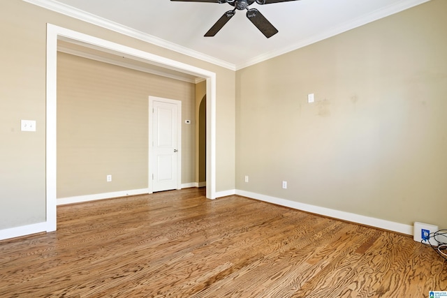 empty room featuring ornamental molding, a ceiling fan, baseboards, and wood finished floors