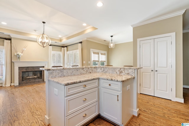 kitchen with hanging light fixtures, light wood finished floors, light stone countertops, and a center island