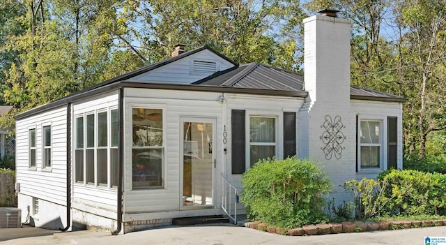 view of front of house with entry steps, metal roof, a chimney, and central AC unit