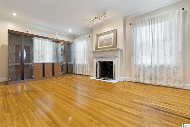 unfurnished living room with baseboards, a fireplace, crown molding, and hardwood / wood-style floors