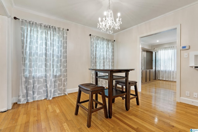 dining room featuring baseboards, light wood-type flooring, a notable chandelier, and crown molding