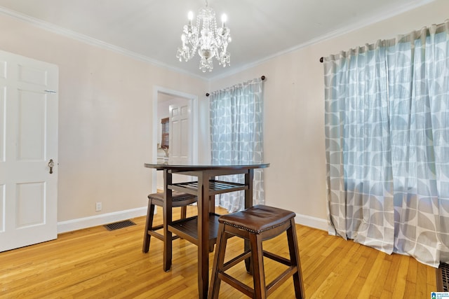 dining area featuring baseboards, visible vents, light wood-style flooring, ornamental molding, and a notable chandelier