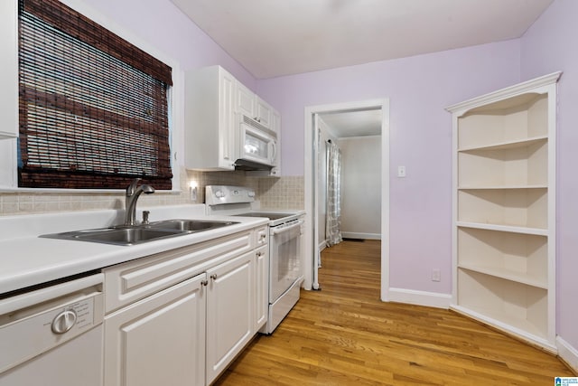 kitchen featuring white appliances, a sink, white cabinets, light wood-style floors, and light countertops