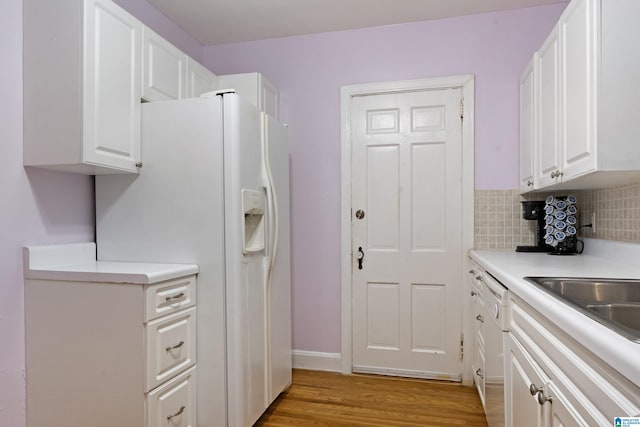 kitchen with white appliances, light wood-style flooring, white cabinets, and backsplash