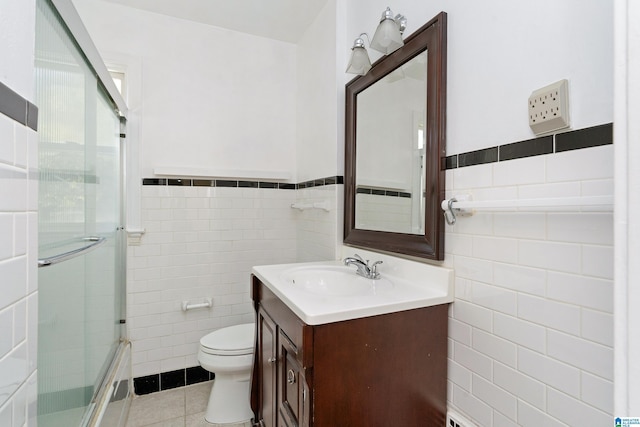 bathroom featuring tile patterned flooring, a shower with door, tile walls, and vanity