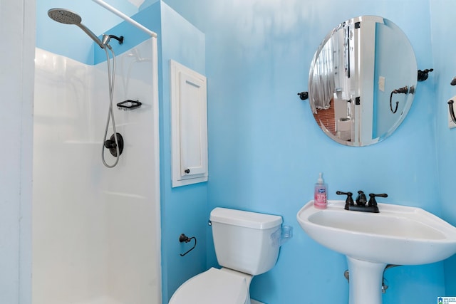 bathroom featuring a sink, a shower stall, and toilet