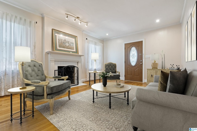 living room with light wood-style floors, a fireplace, crown molding, and recessed lighting