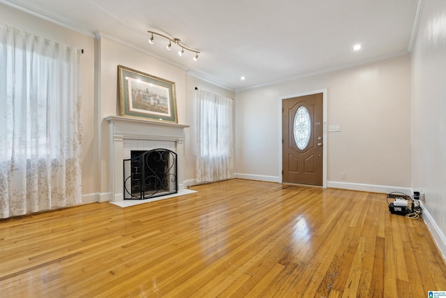 foyer featuring recessed lighting, a tiled fireplace, ornamental molding, baseboards, and hardwood / wood-style flooring