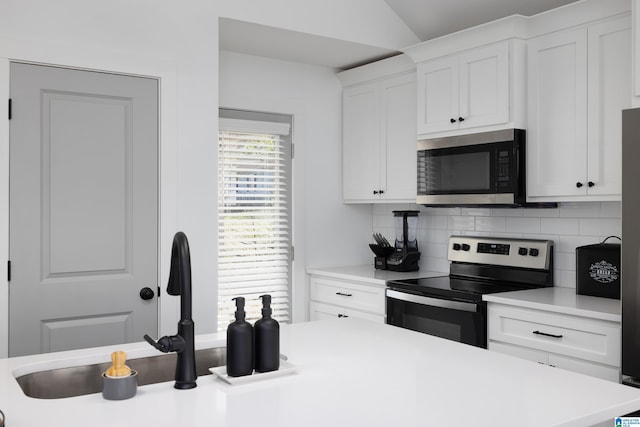 kitchen with light countertops, appliances with stainless steel finishes, white cabinetry, and decorative backsplash