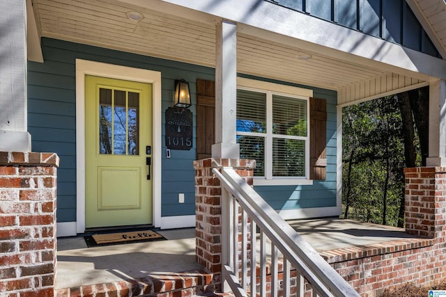 doorway to property with covered porch and brick siding