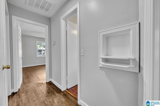 corridor featuring visible vents, baseboards, and wood finished floors