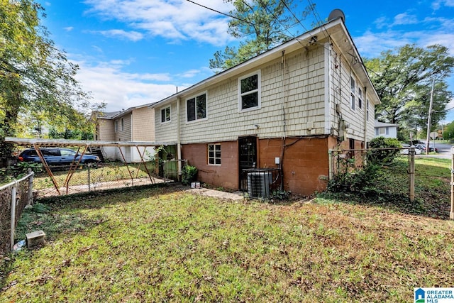 back of property featuring central AC, a lawn, and fence