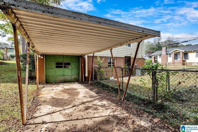 view of car parking with driveway, fence, and a carport