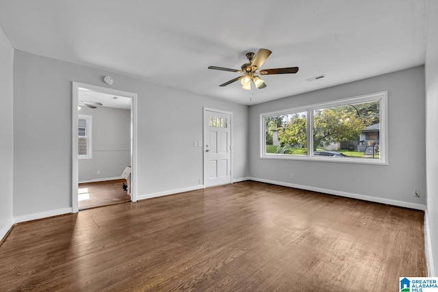 empty room featuring a ceiling fan, wood finished floors, visible vents, and baseboards