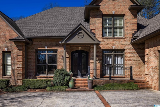 view of front of home featuring roof with shingles, french doors, and brick siding