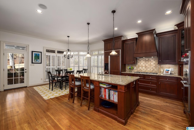 kitchen featuring ornamental molding, wood finished floors, decorative backsplash, and custom range hood