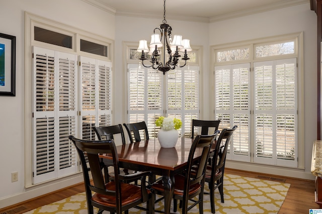 dining room featuring ornamental molding, light wood-type flooring, a chandelier, and visible vents