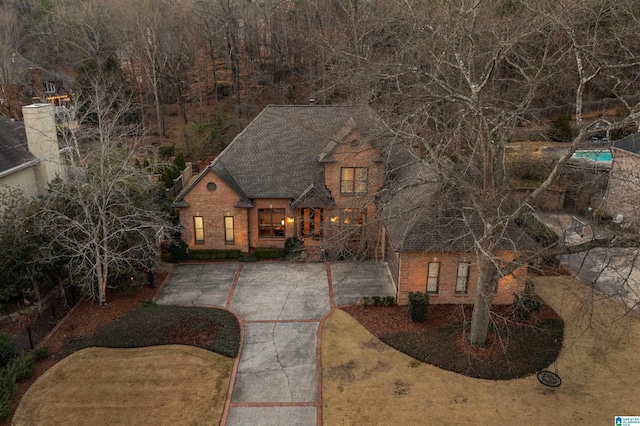 view of front of home featuring brick siding, driveway, and roof with shingles