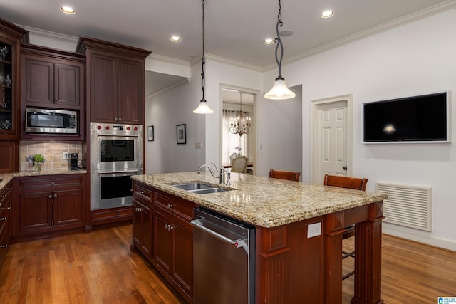 kitchen featuring a sink, visible vents, appliances with stainless steel finishes, dark wood-style floors, and a kitchen bar