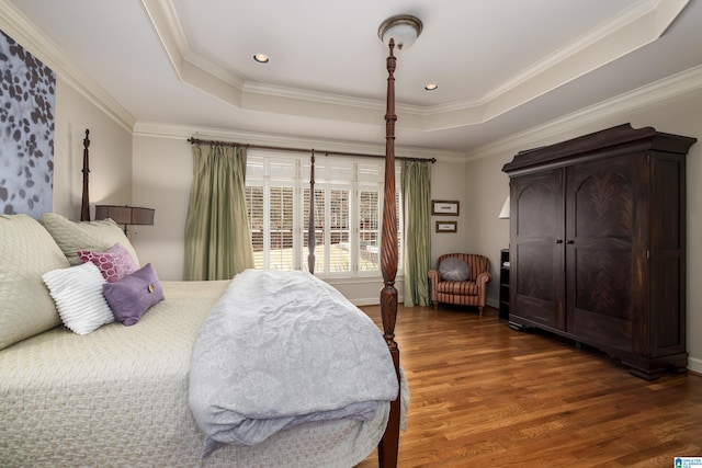 bedroom featuring ornamental molding, a tray ceiling, recessed lighting, and wood finished floors