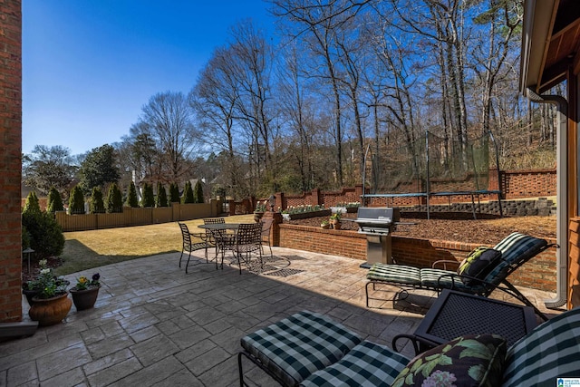 view of patio featuring a fenced backyard, a trampoline, grilling area, and outdoor dining space