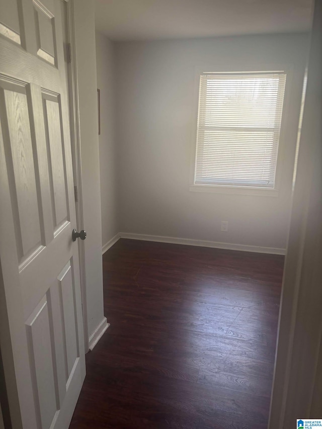 empty room with dark wood-style floors and baseboards