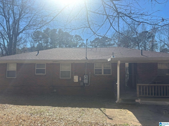 back of house featuring crawl space, roof with shingles, and brick siding