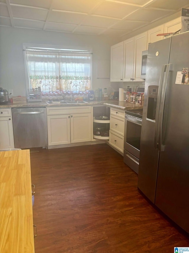 kitchen with appliances with stainless steel finishes, dark wood finished floors, white cabinets, and a sink