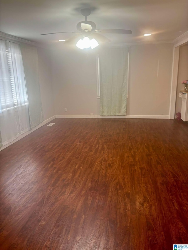 spare room featuring baseboards, ornamental molding, dark wood finished floors, and a ceiling fan