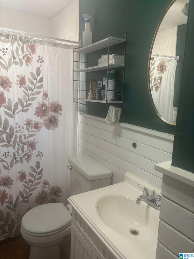 bathroom featuring wood walls, vanity, toilet, and a shower with curtain