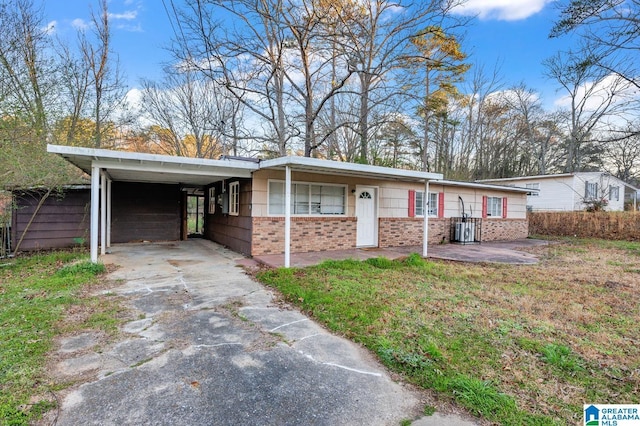 single story home with a carport, driveway, brick siding, and a front lawn